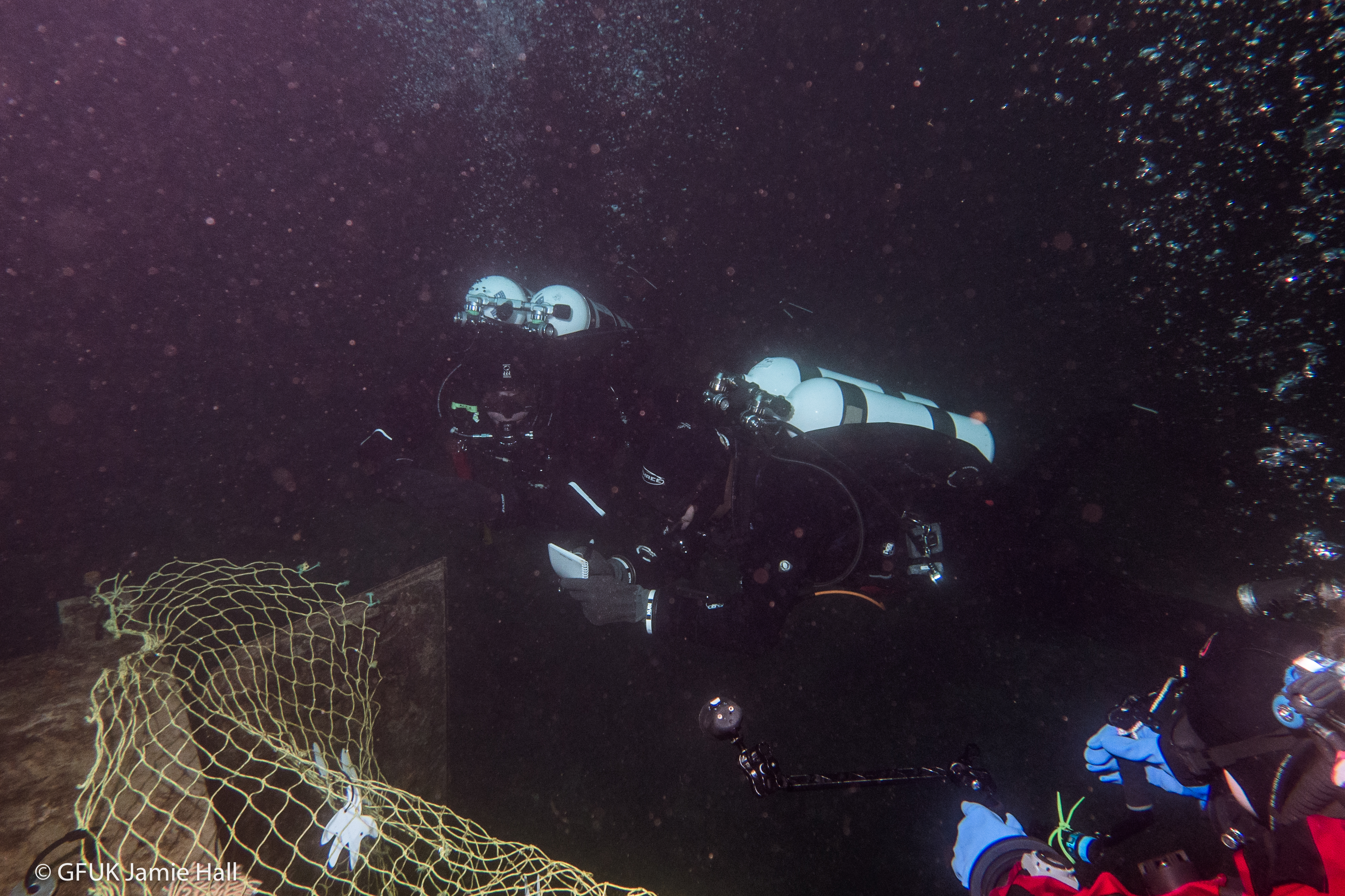 Two divers survey a mocked-up ghost net
